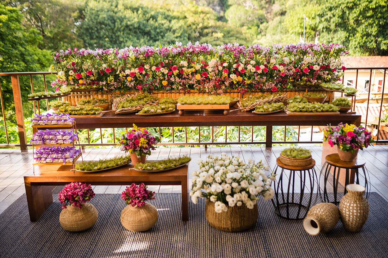Mesas na varanda com com flores e bandejas com doces