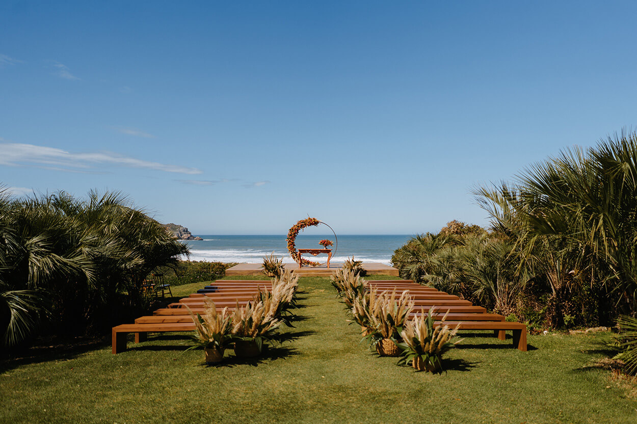 jardim de frente para o mar ocm bancos de madeira com arranjos com capim dos pampas e altar com flores