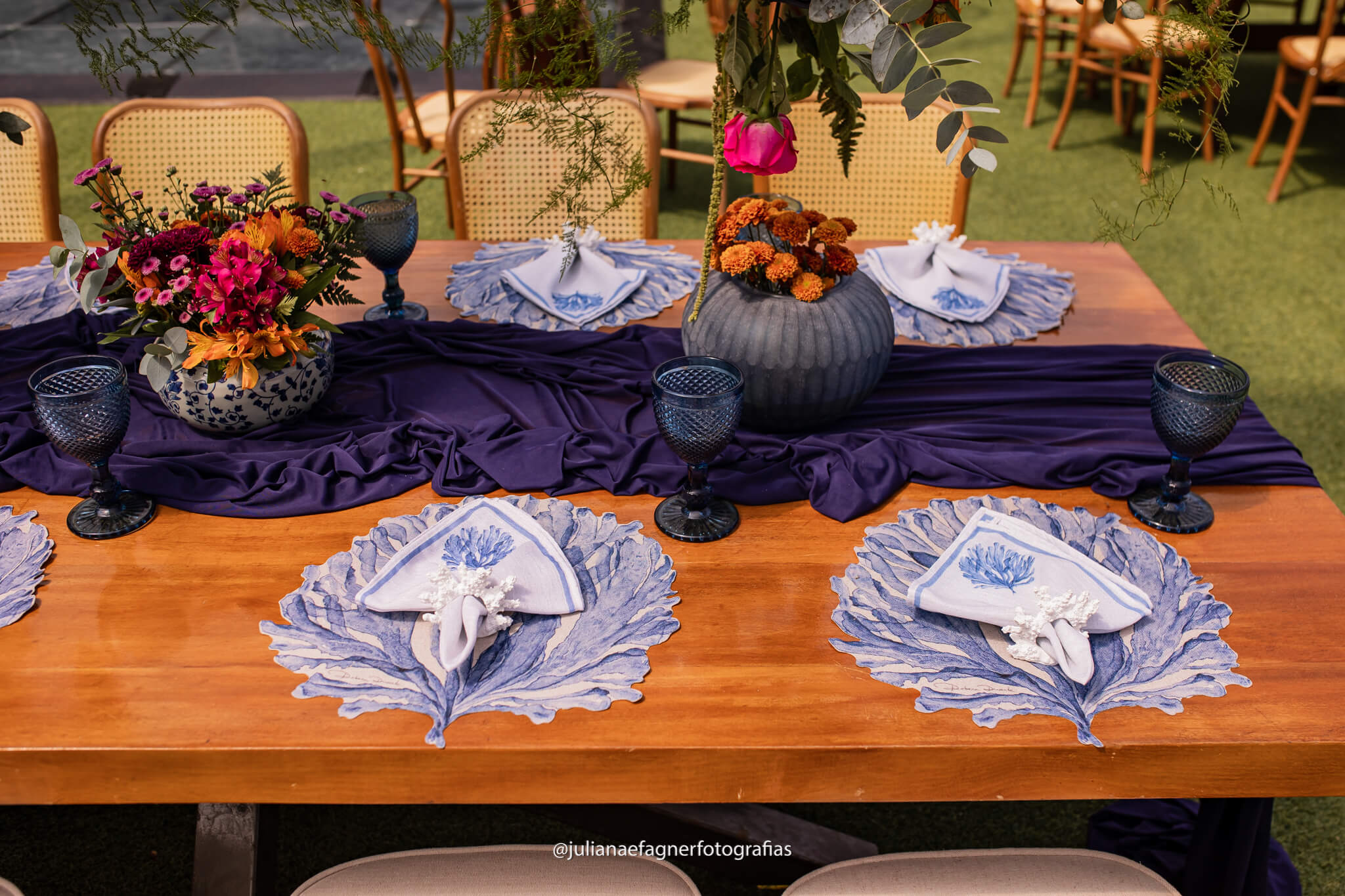 mesa posta com toalha azul no centro e vasos com flores rosas e laranjas