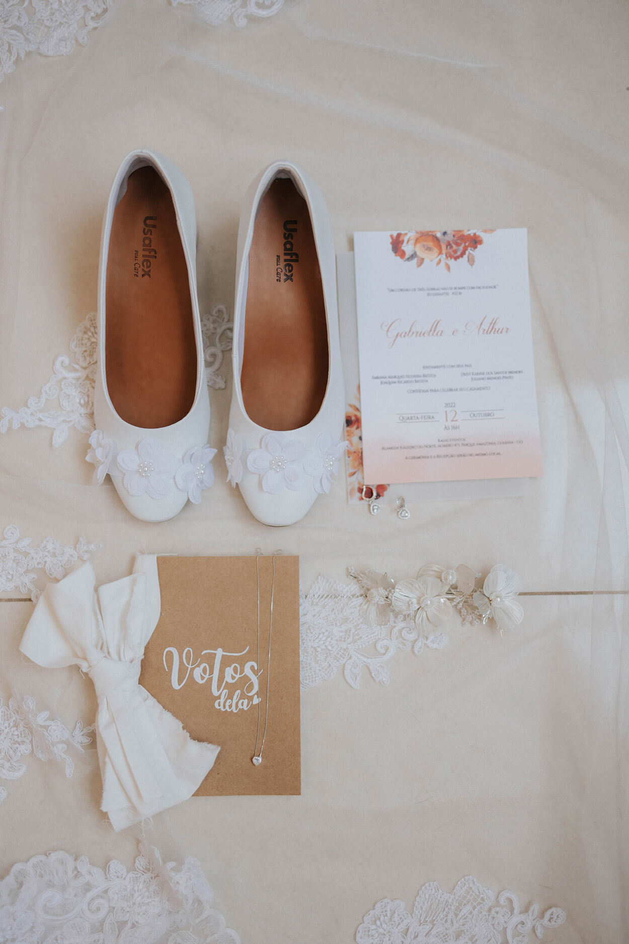 sapatilha branca com flores ao lado de convite de casamento