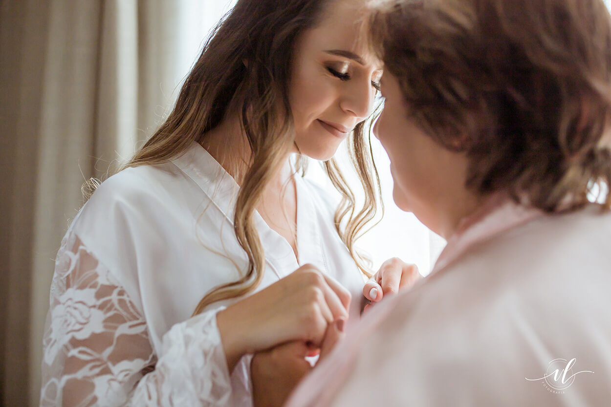 noiva com robe brancp de mãos dadas coma mãe