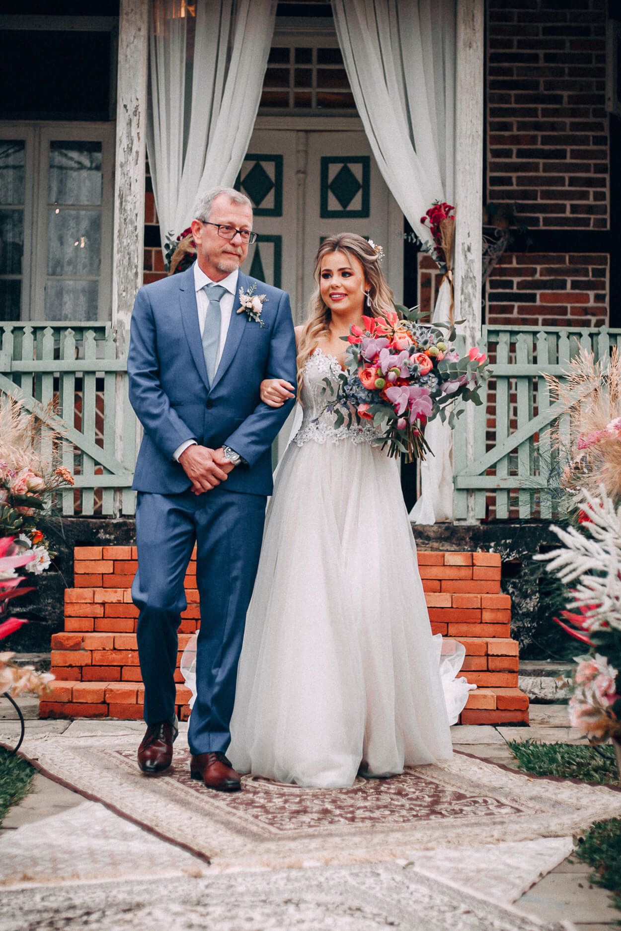 Entrada da noiva ao lado de seu pai com terno azul
