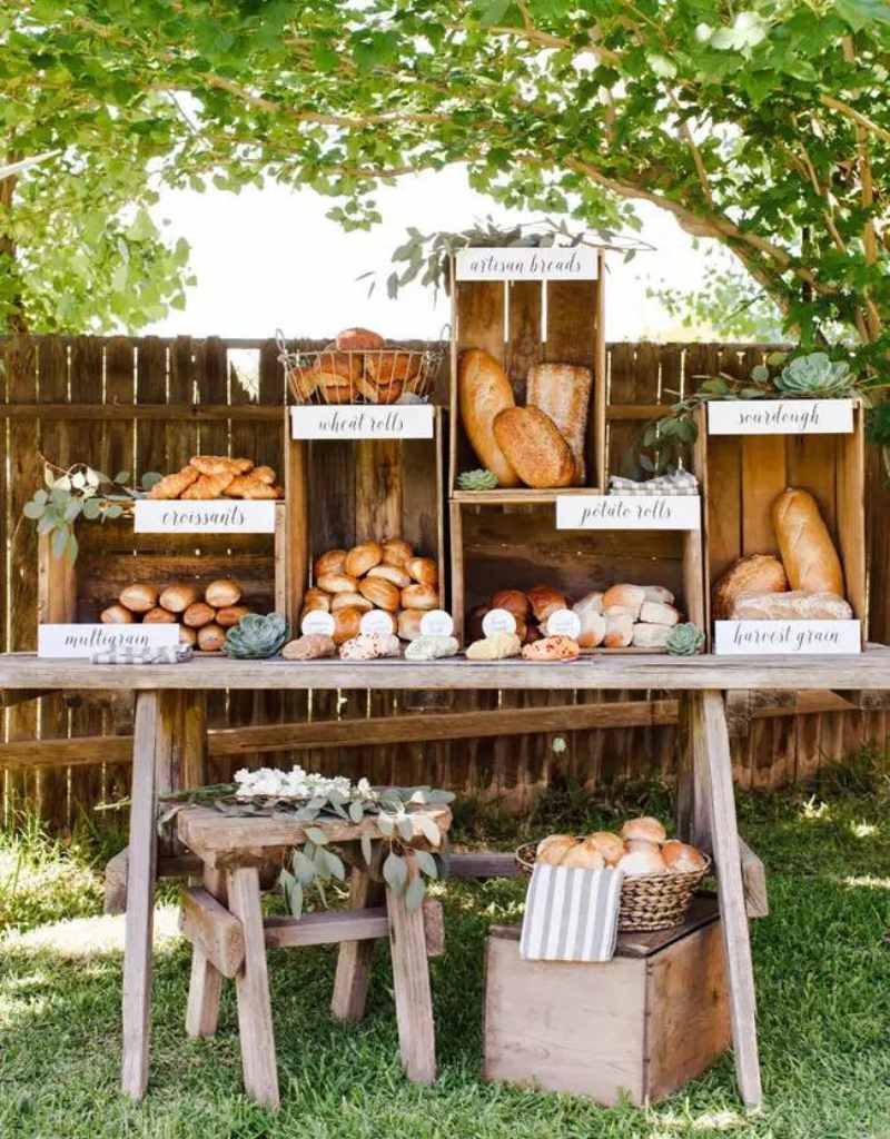 mesa de pães para brunch de casamento rústico disposta em mesa de madeira e caixotes