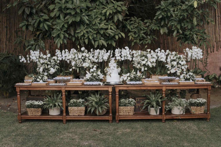mesa do bolo com flores brancas em casamento ao ar livre