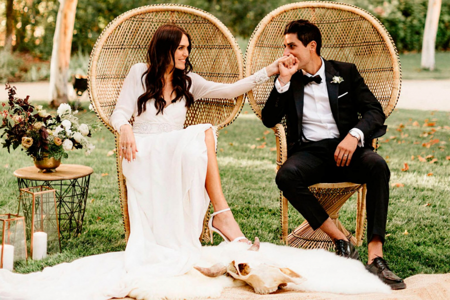 noivos sentados em cadeira pavão em casamento ao ar livre