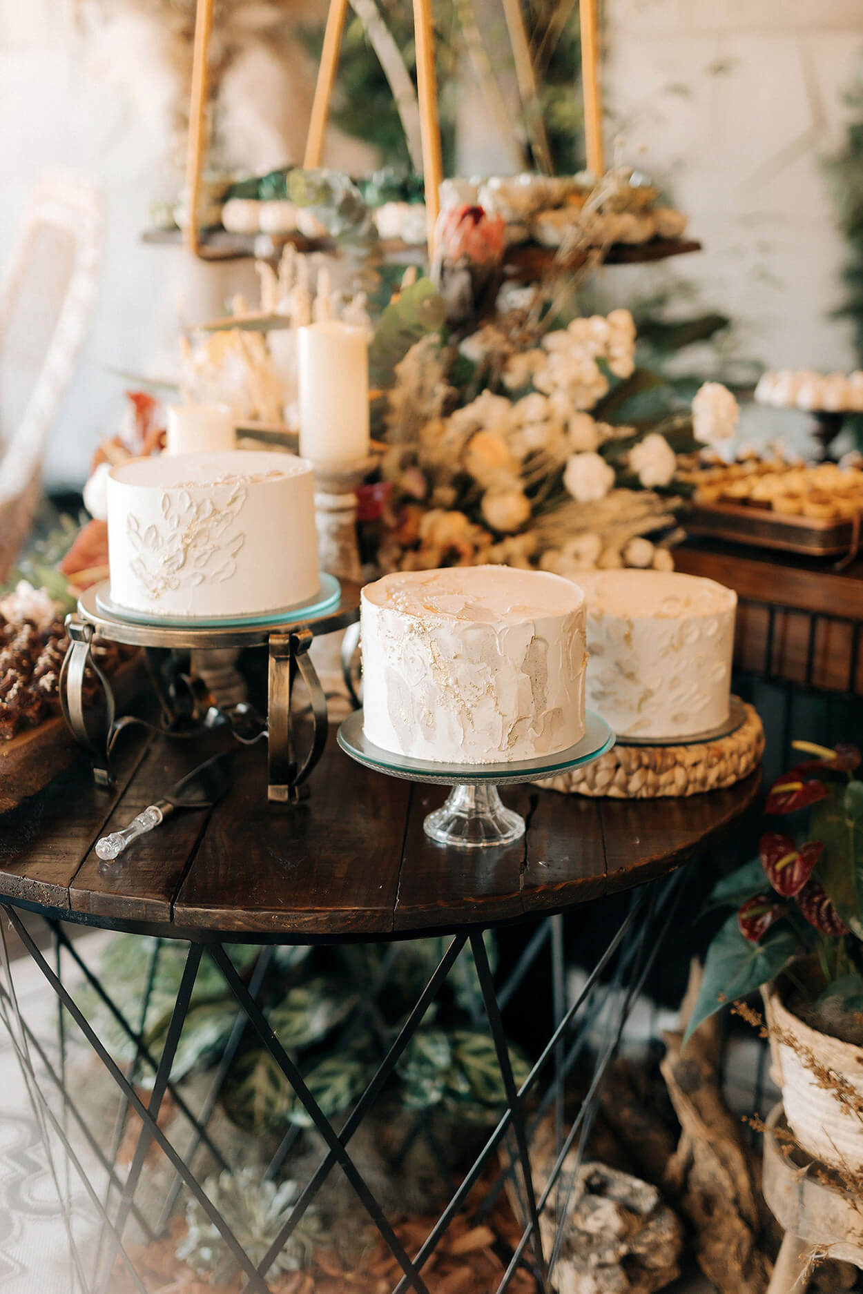 Mesa de madeira com trio de bolos de casamento branco com textura