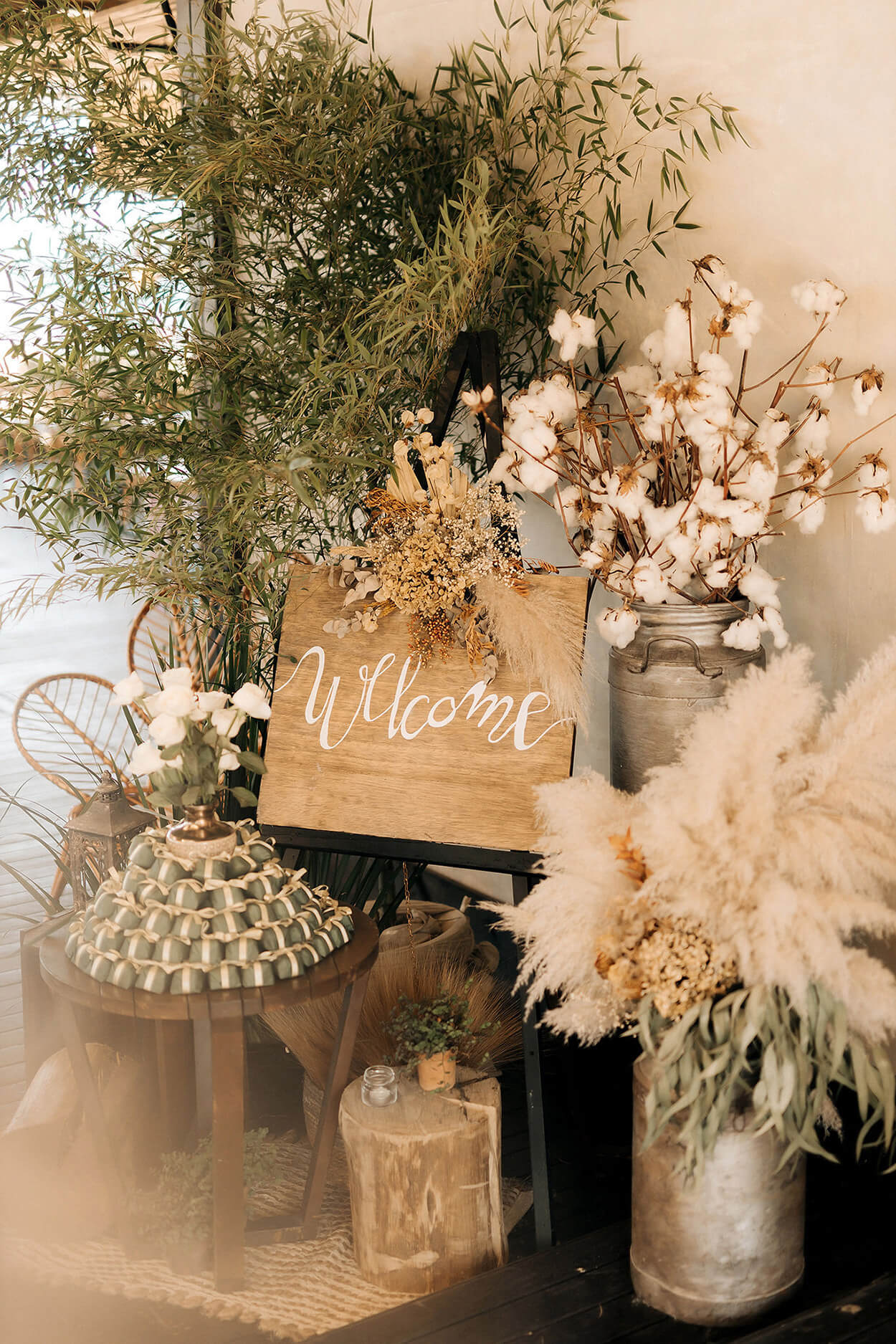 pala de madeira escrito bem vindo ao lado de flores capim dos pampas e bandeja com bem casados