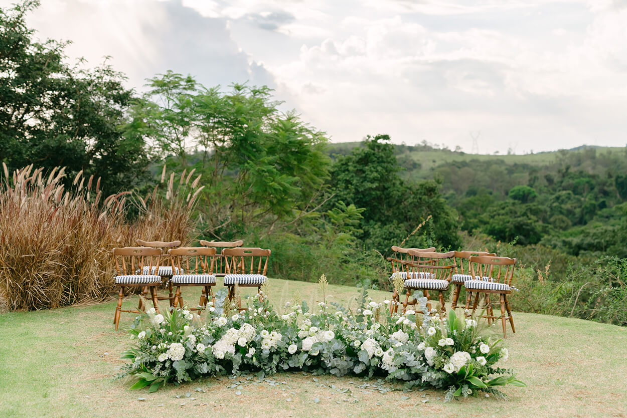 cadeiras no campo e altar com flores brancas no chão