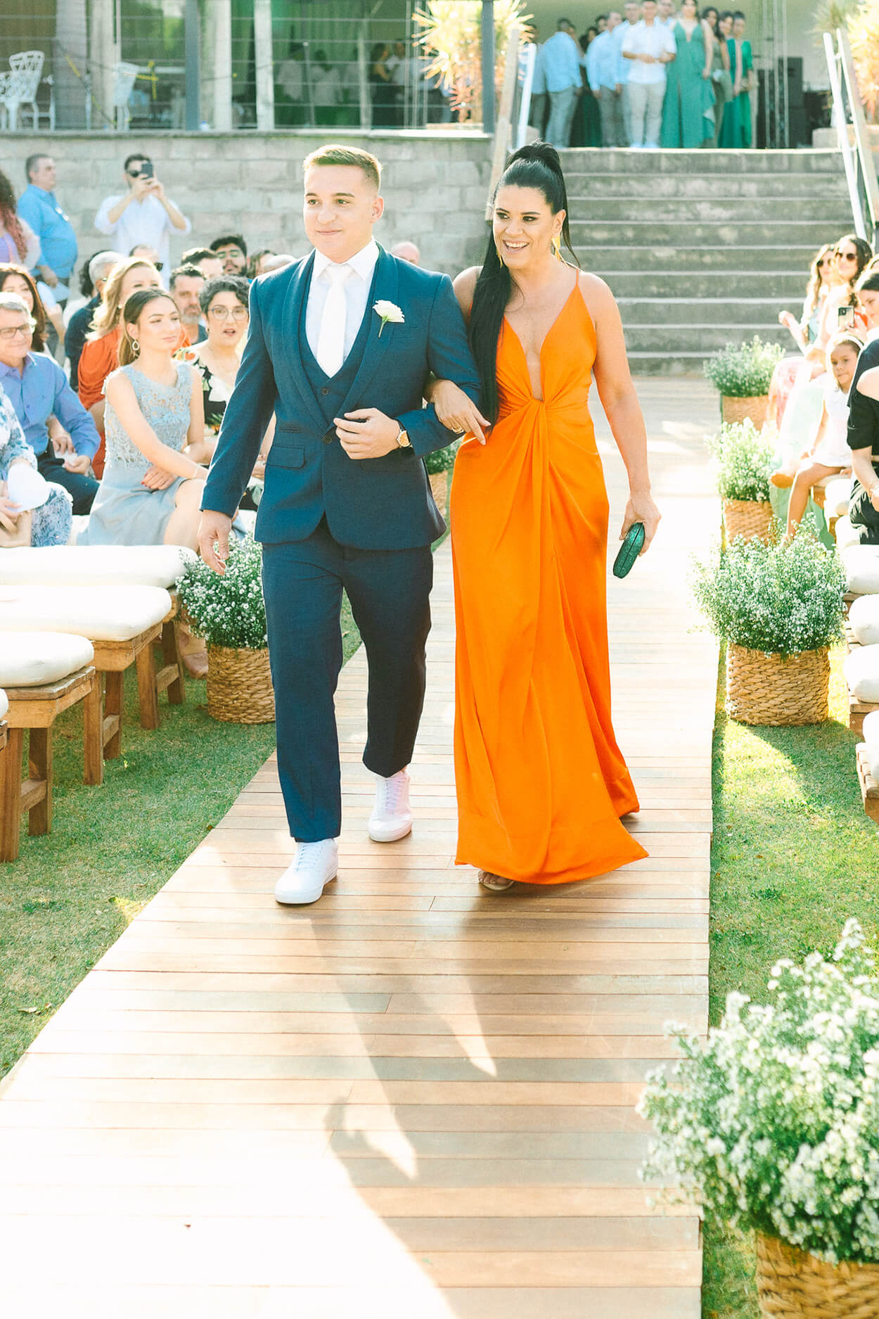 noivo com terno azul ao lado da mãe com vestido laranja