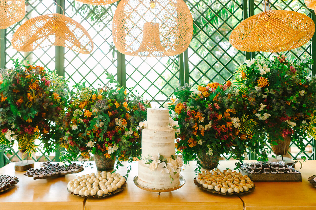 Mesa do bolo com bolo de três andares semi espatulado branco com bandeja com doces