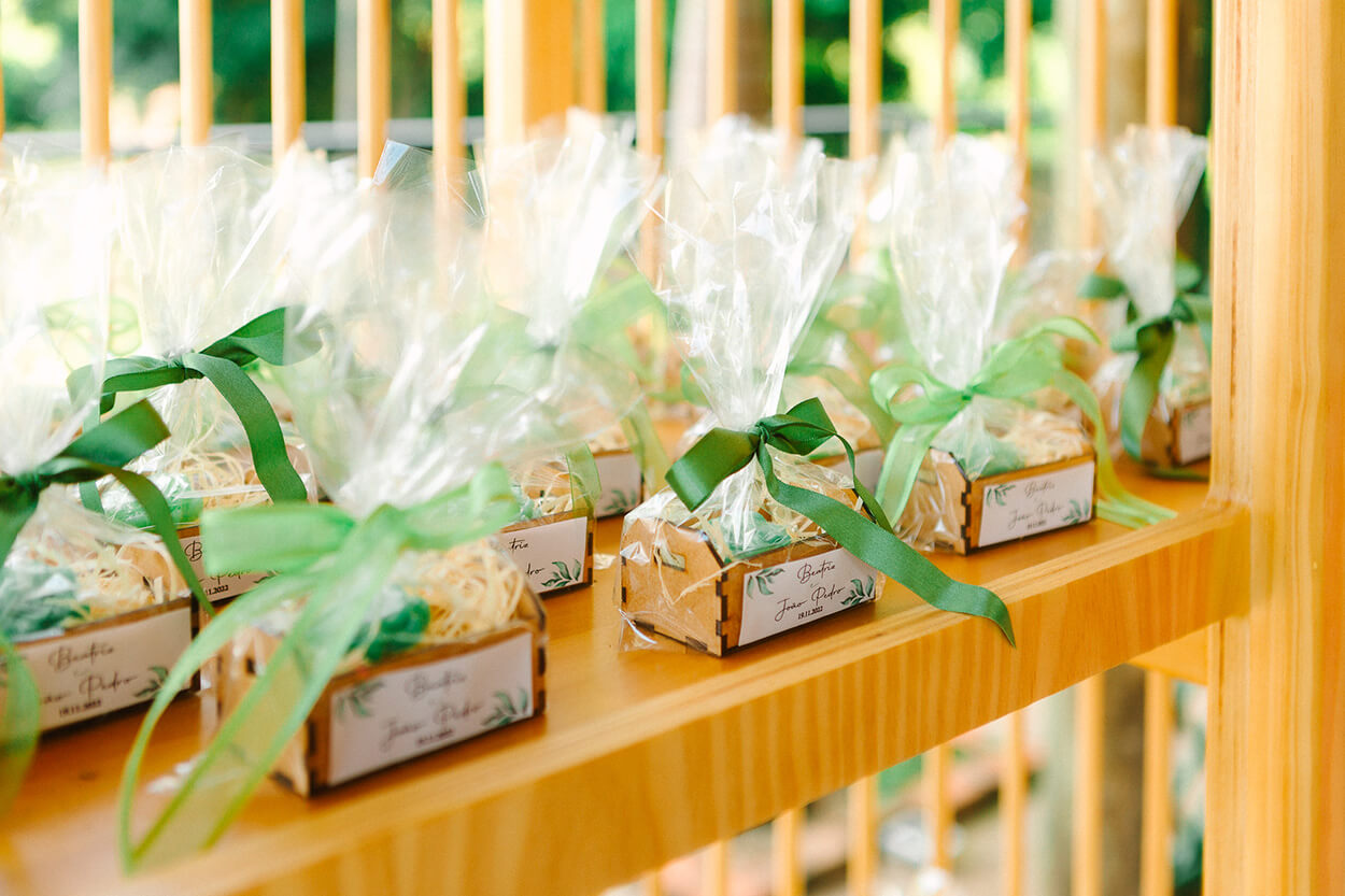 estante de madeira com lembrancinhas com caixinhas de madeira com laço verde