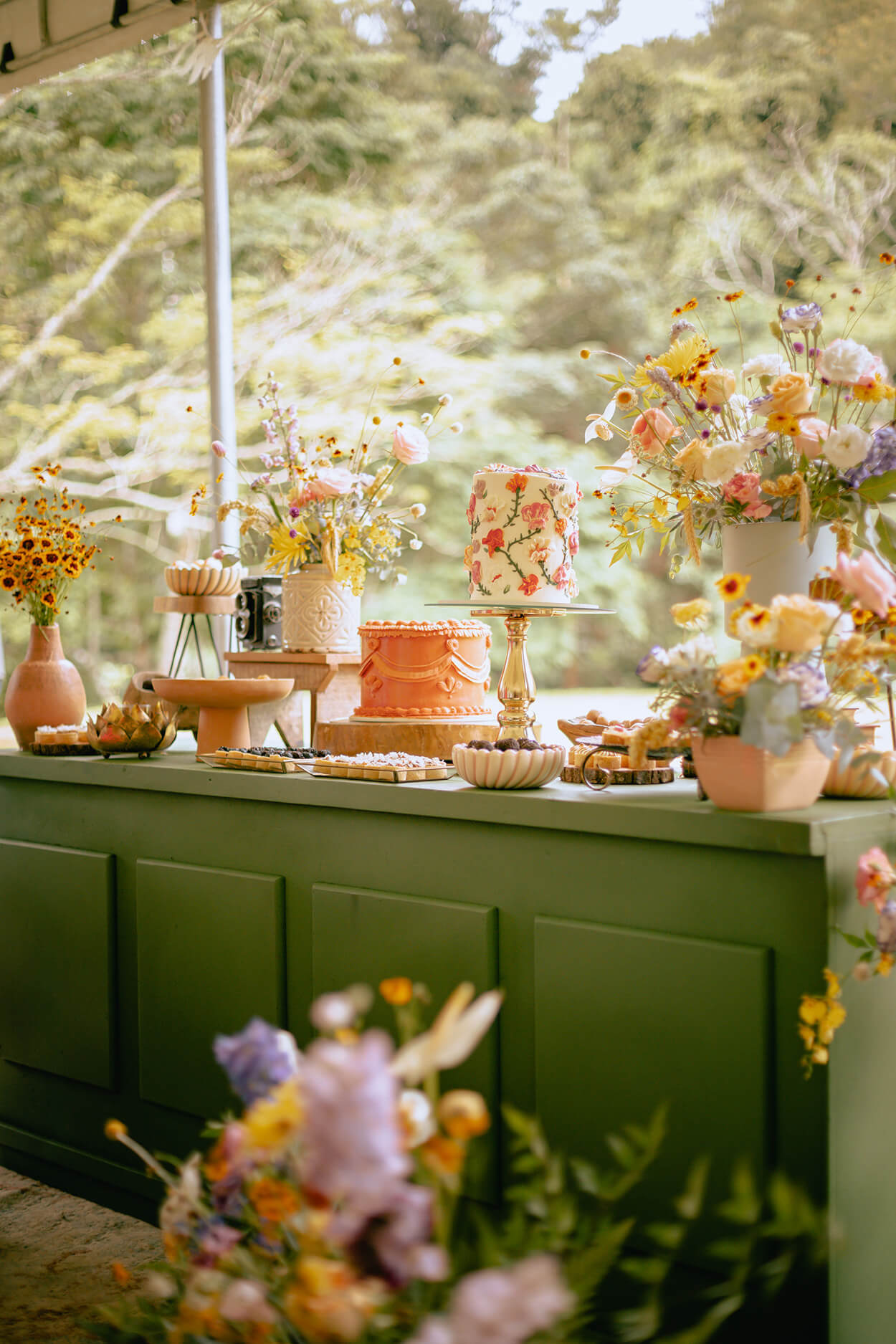 mesa verde com doces flores e bolo de casamento laranja