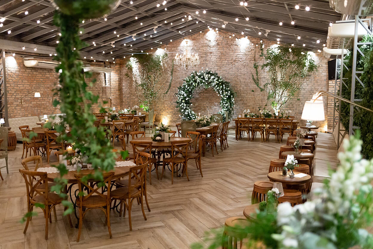 salão rustico com mesas redondas de madeira e altar com flores brancas