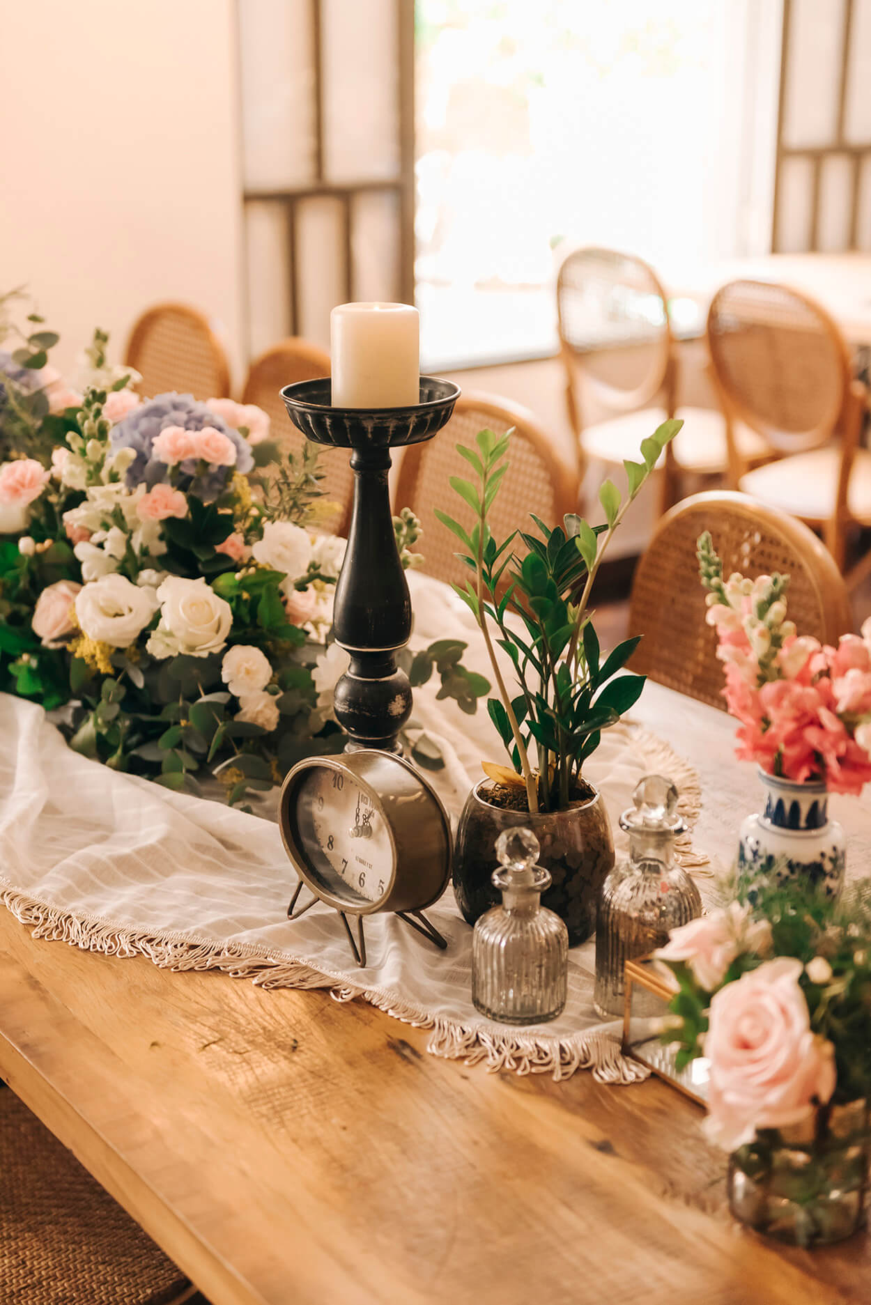 Mesa de madeira com toalha branca no centro castiçal com vela e flores brancas e rosas