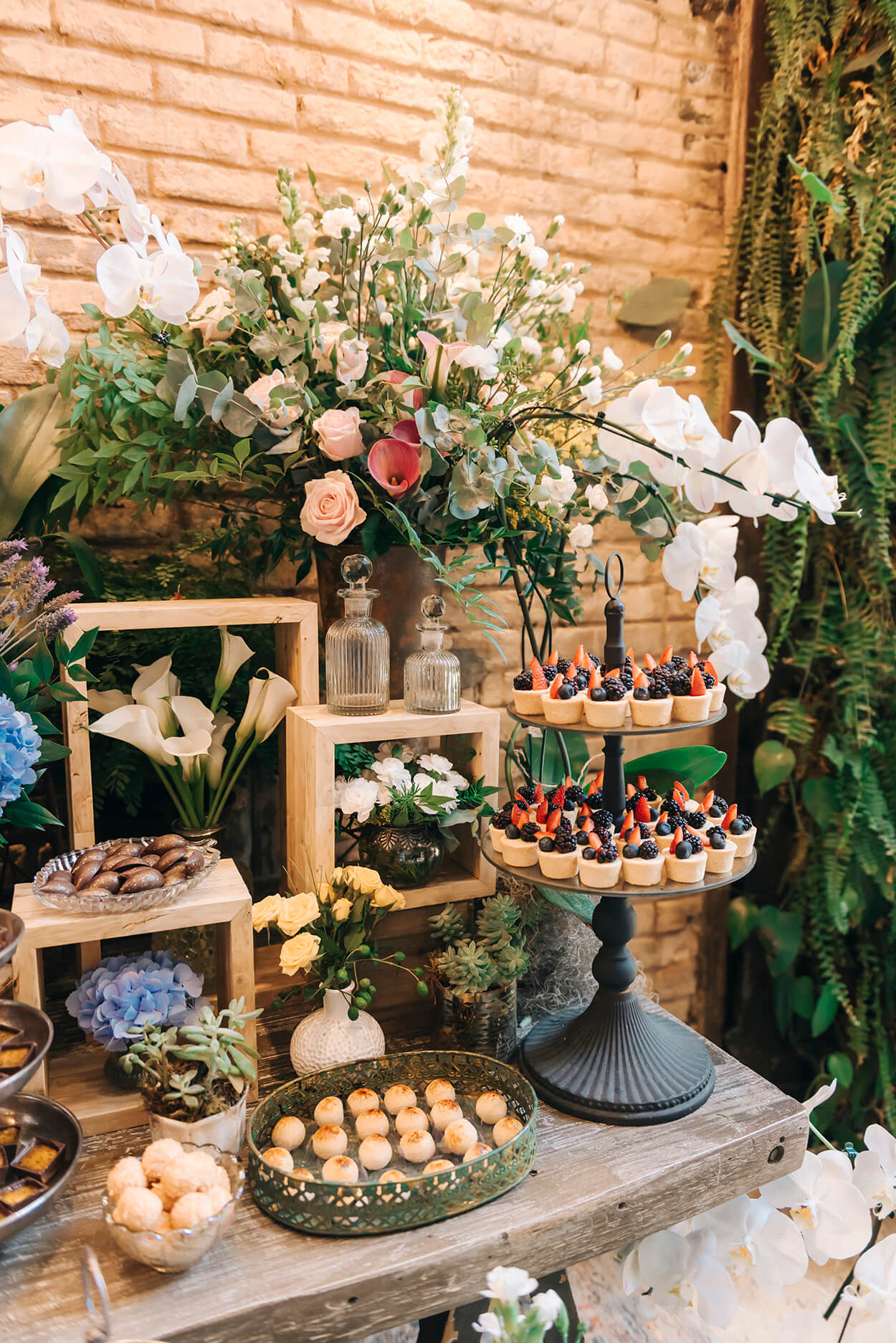Mesa com bandejas com doces de casamento e flores