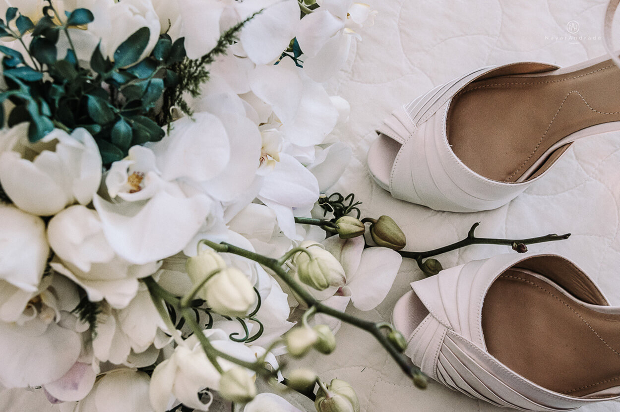 buquê com flores brancas e orquideas ao lado de sapato branco