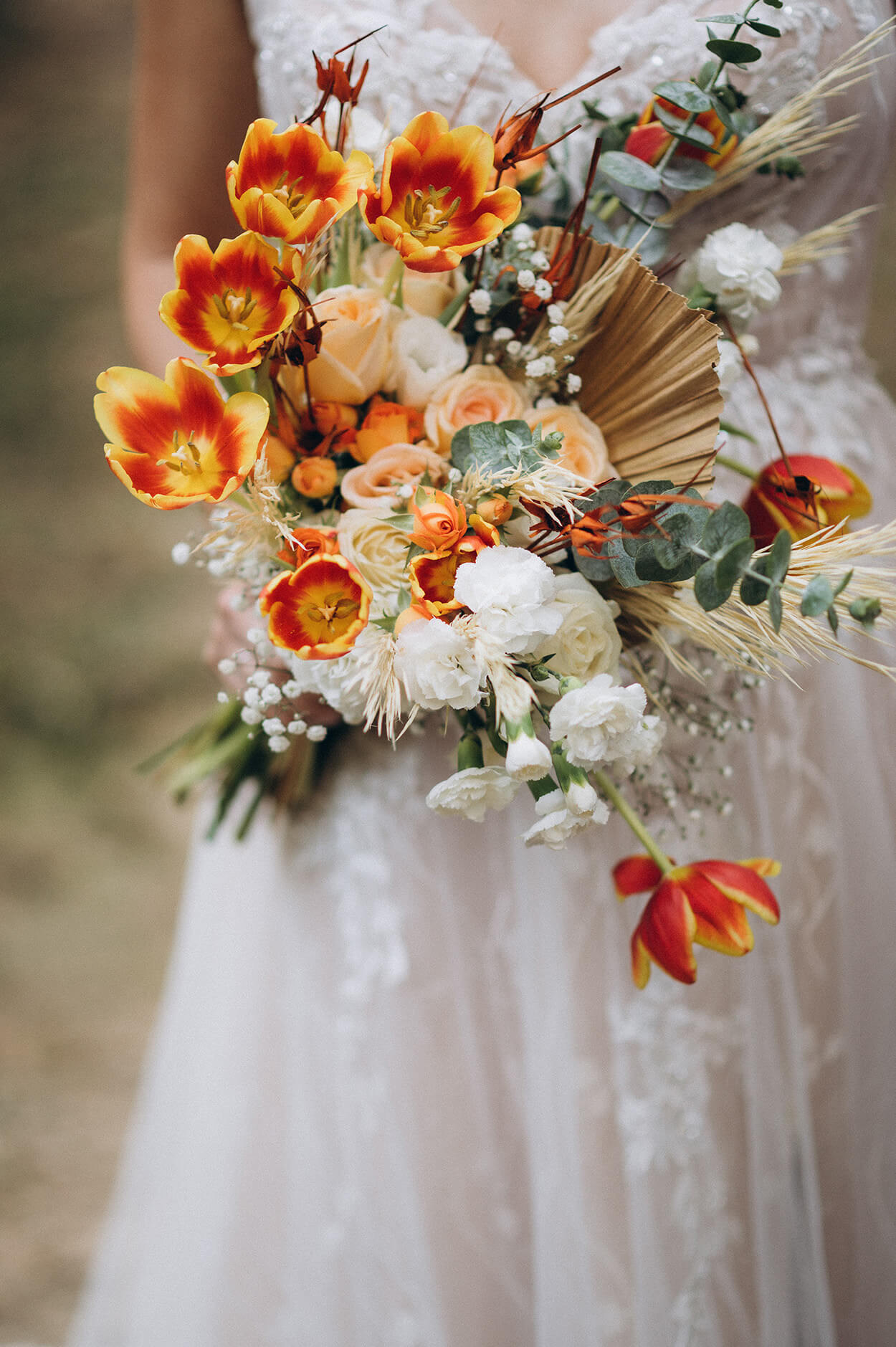 noiva segurando buquê com flores brancas e laranjas