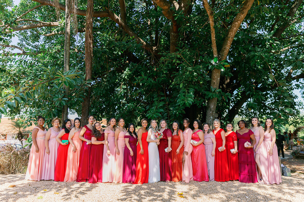 noiva ao lado das madrinhas com vestidos cor de rosa e vermelho