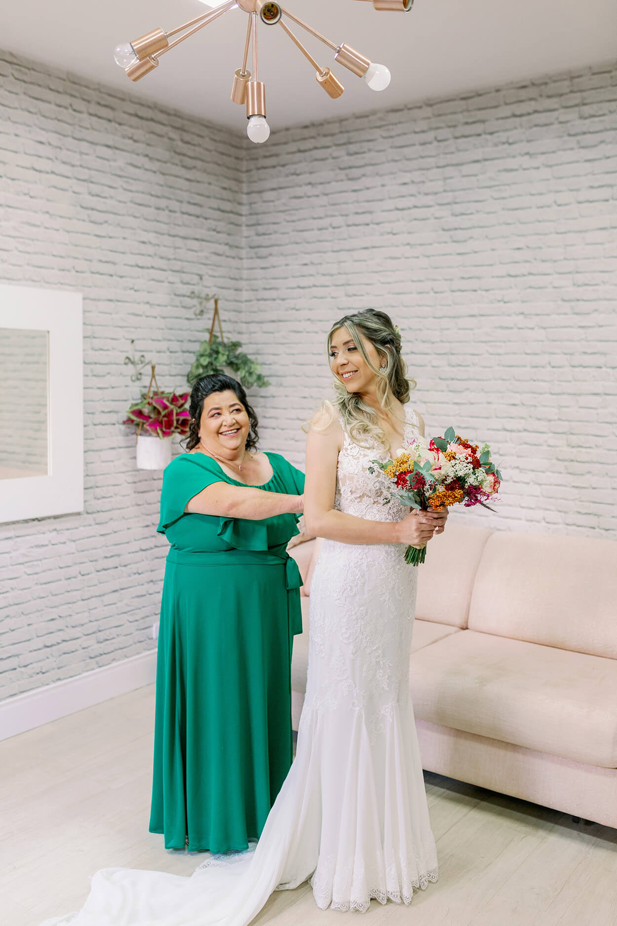 Mãe da noiva com vestido verde arrumando a noiva