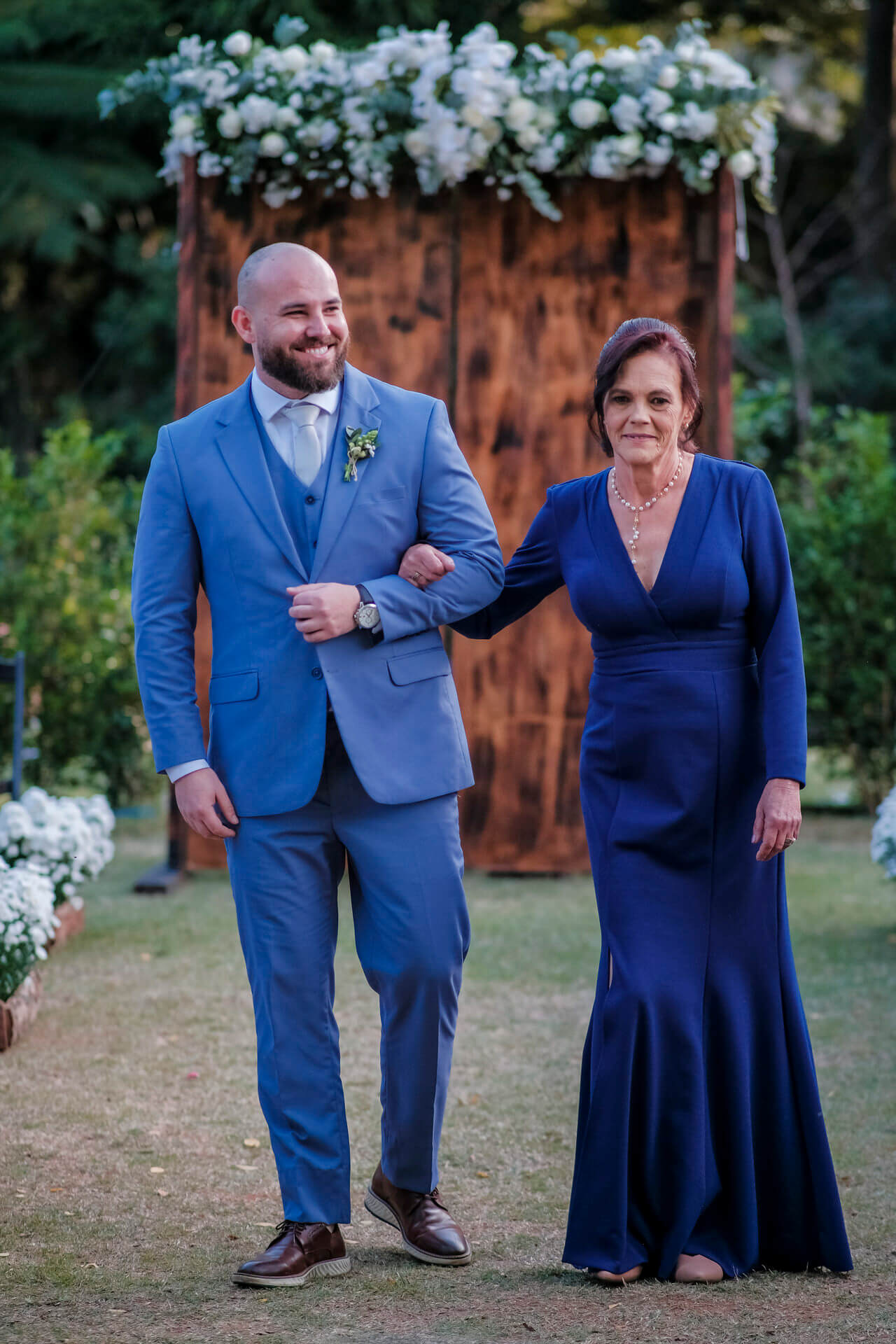 entrada do noivo ao lado da mãe com vestido azul escuro longo