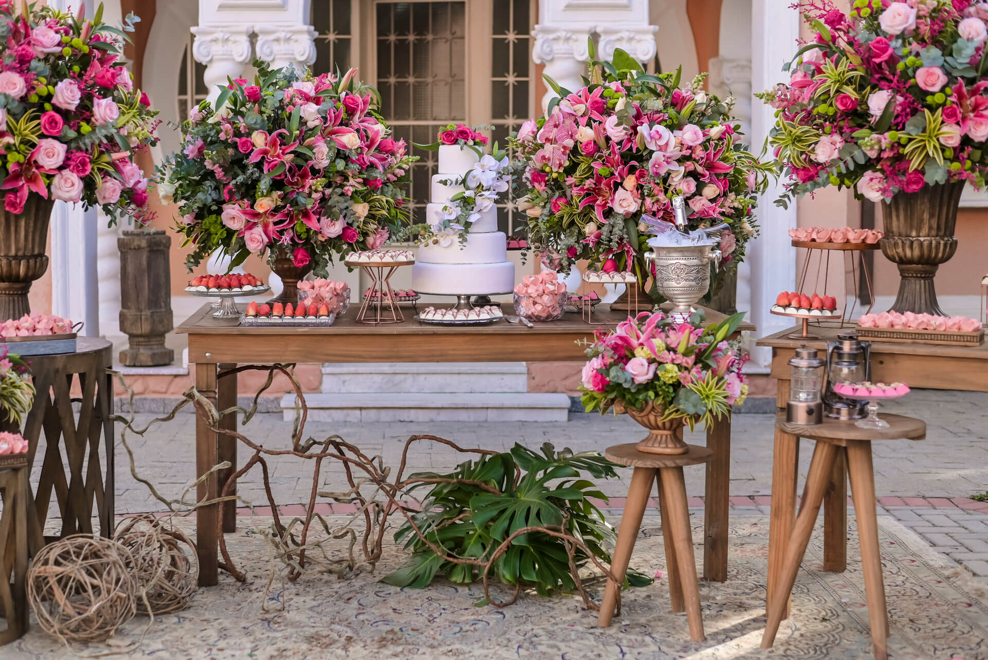 Mesas de madeira com bolo de casamento com cinco andares com flores cor de rosa e orquídeas 