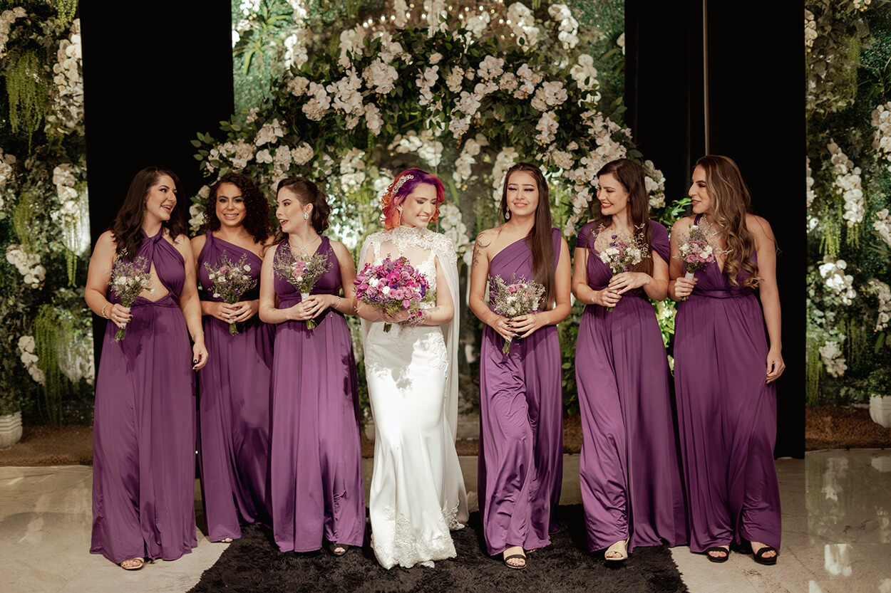 noiva e madrinhas com vestidos roxos segurando buquês