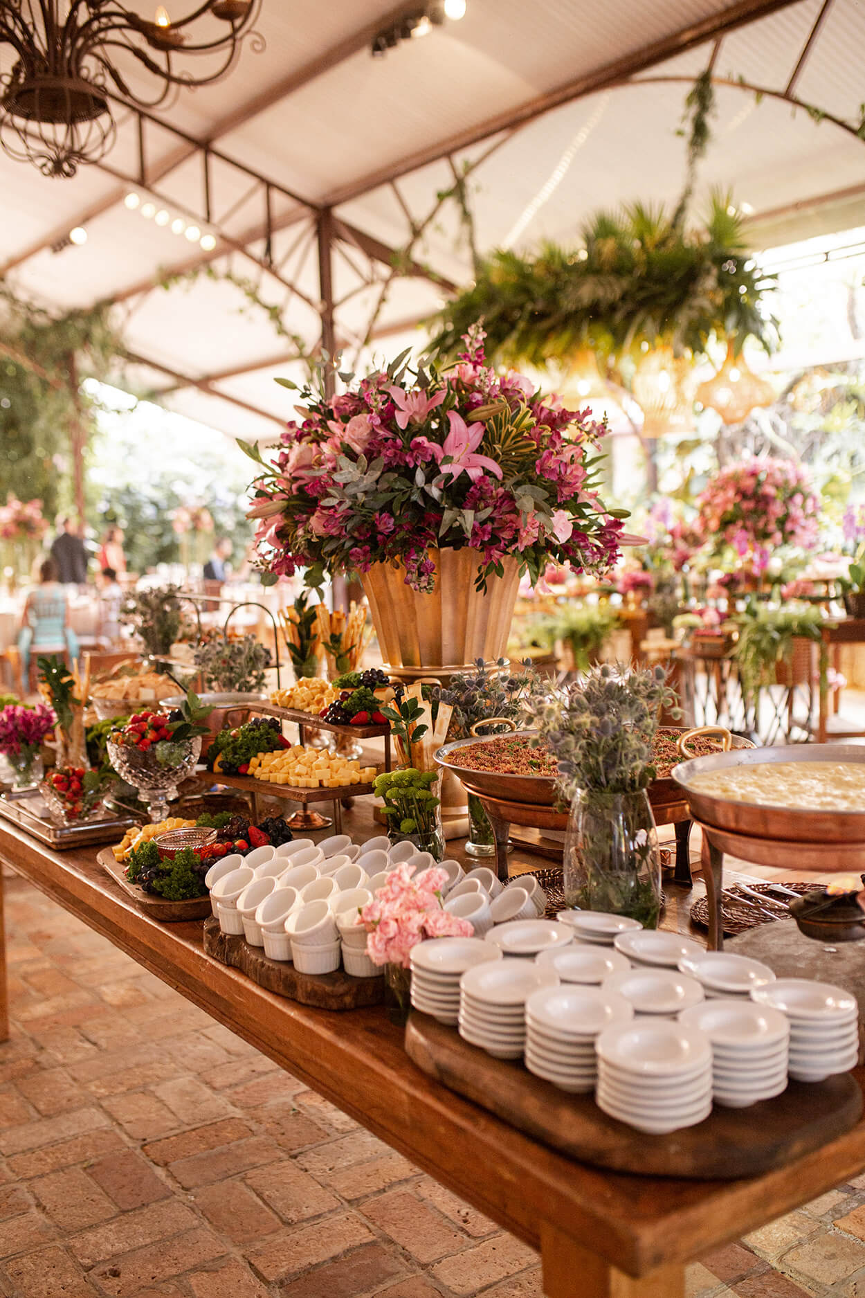 Mesa com copos pratos e vasos com flores cor de rosa