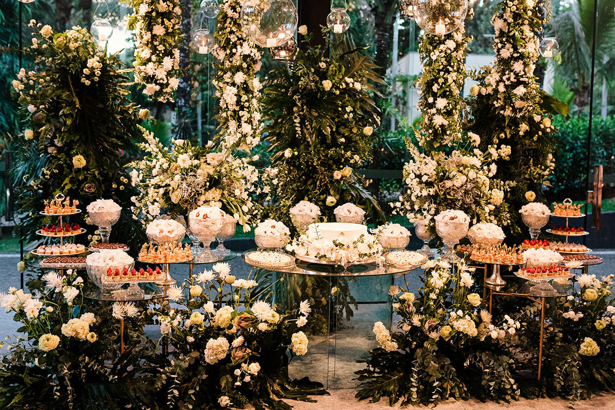 mesa de vidro e bolo de casamento branco e taças com doces de casamento