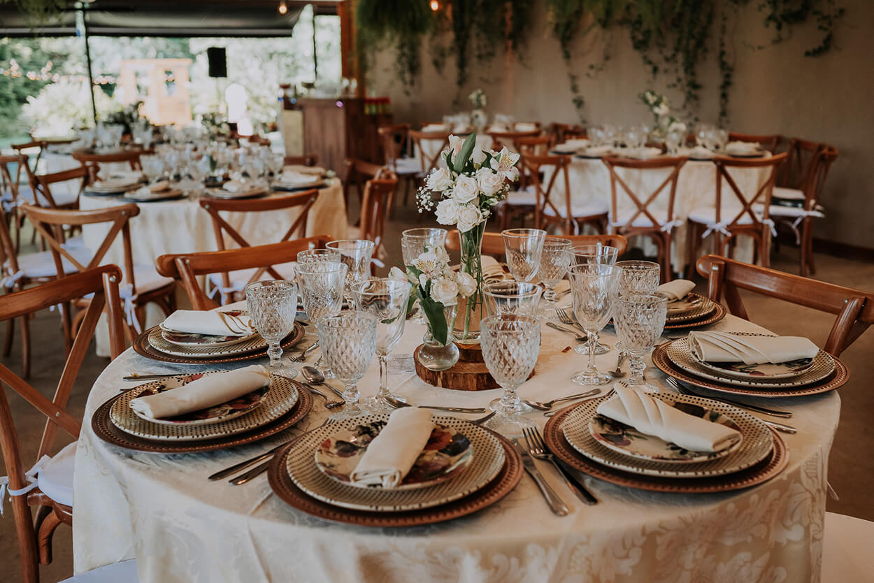 mesa posta com toalha branca e vaso com flores brancas no centro