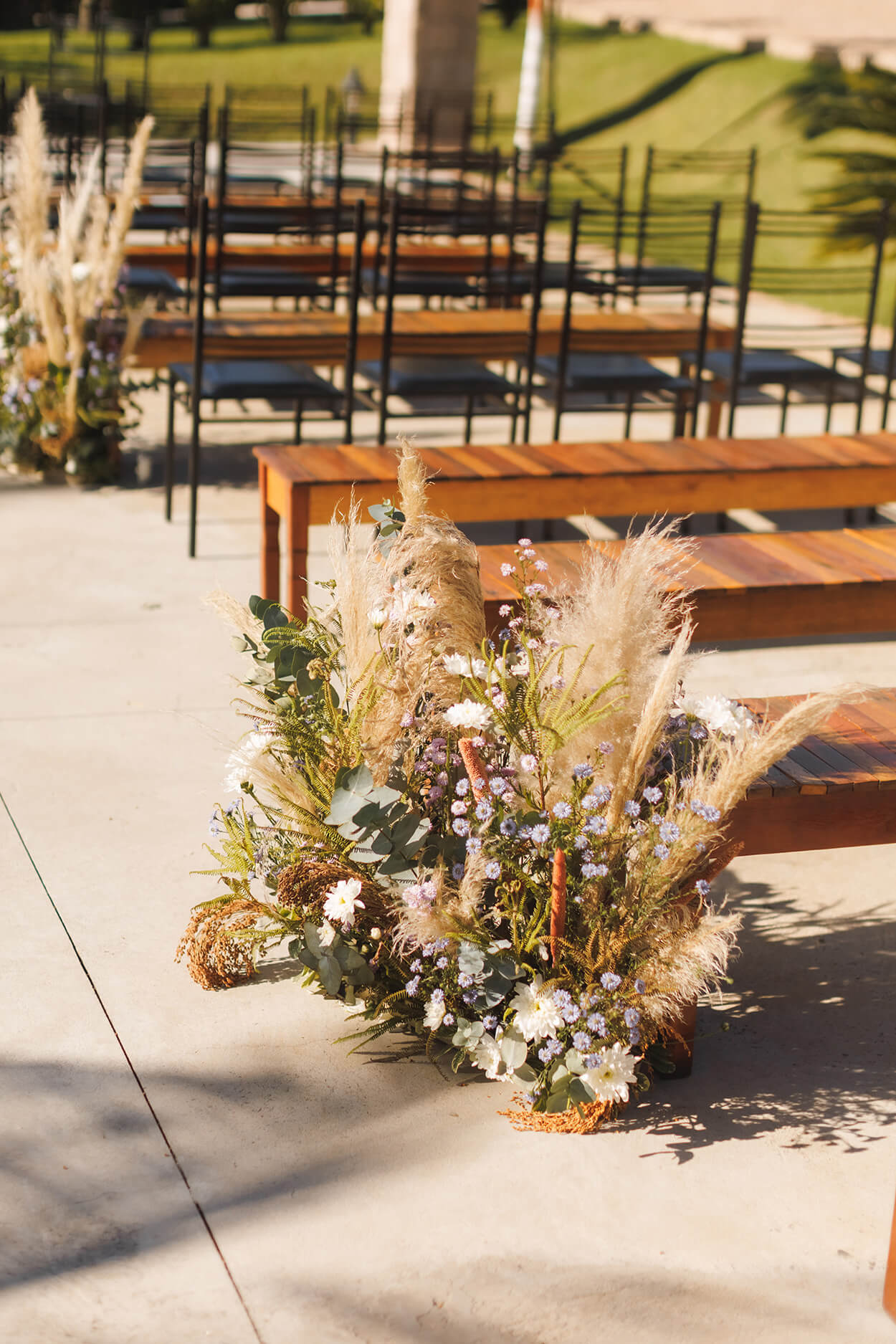 bancos de madeira com capim dos pampas com flores lilás