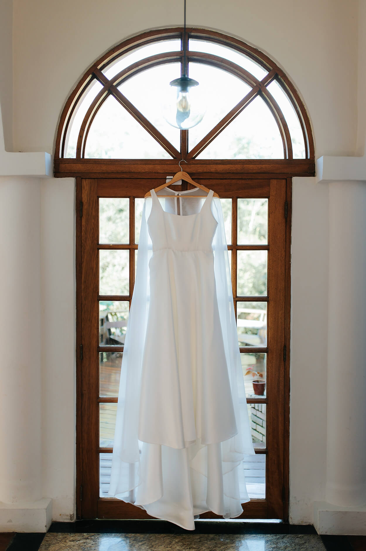 vestido de noiva pendurado no cabide na frente de janela