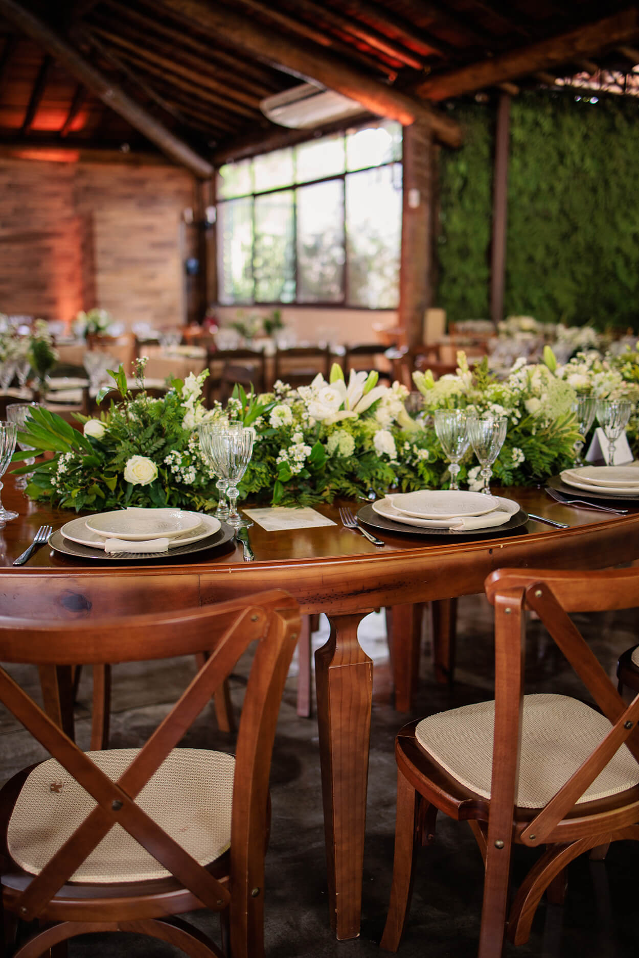 salão rústico com mesas de madeira com flores brancas