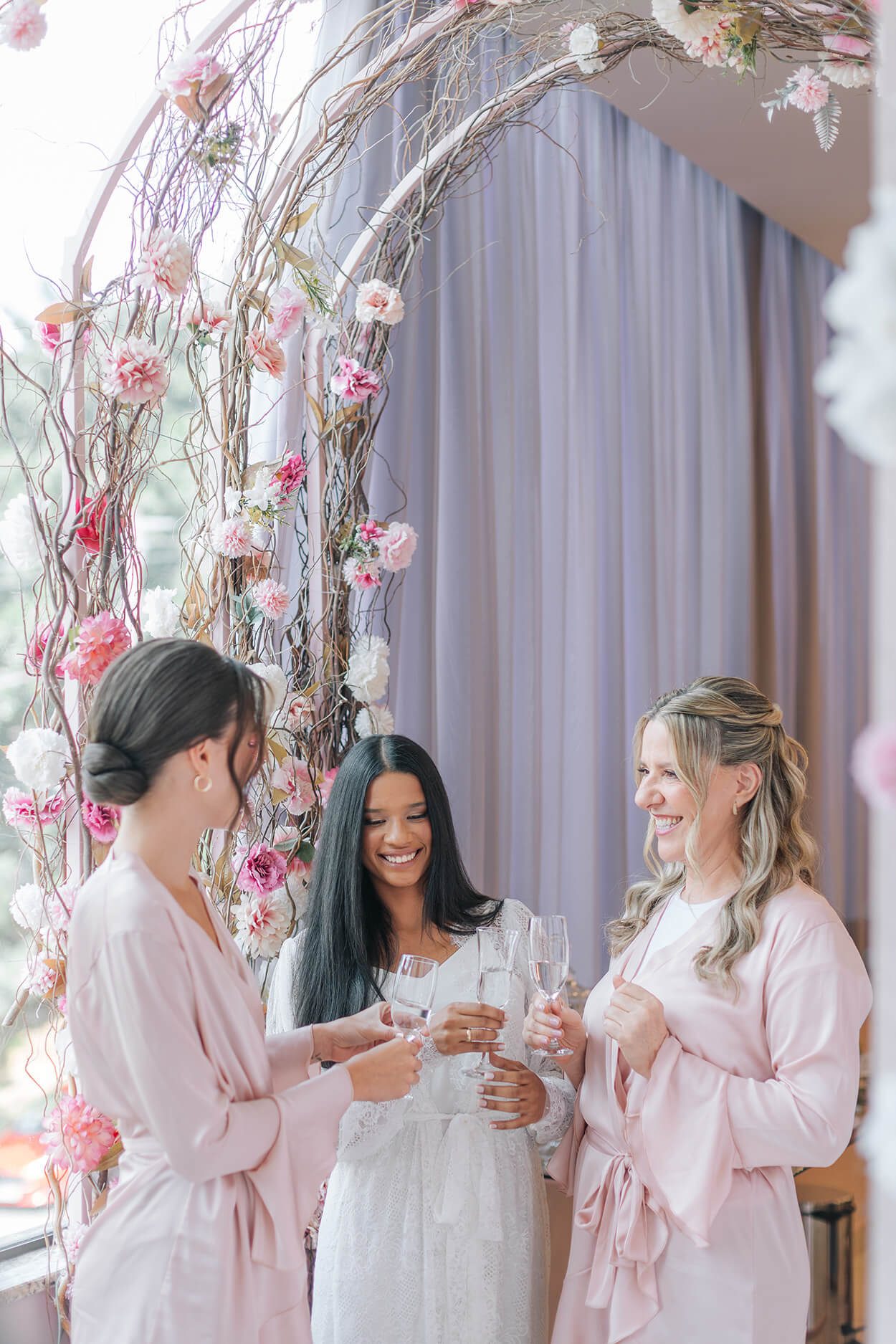 noiva e madrinhas com robes cor de rosa brindando