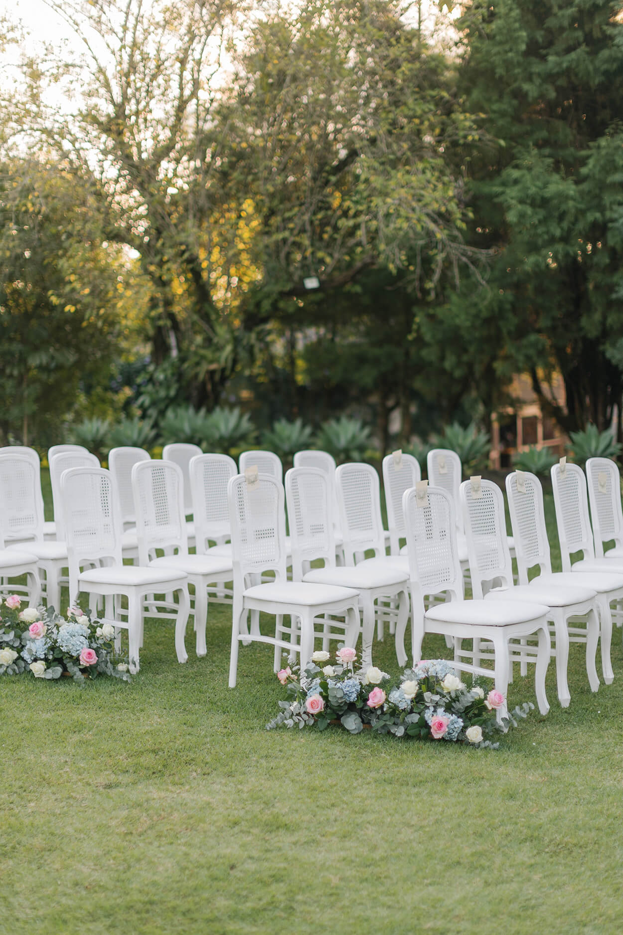 cadeiras brancas no jadrim com arranjos de flores