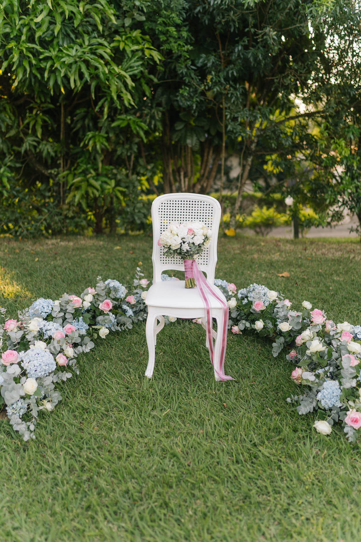 cadeira branca com buquê com fita cor de rosa