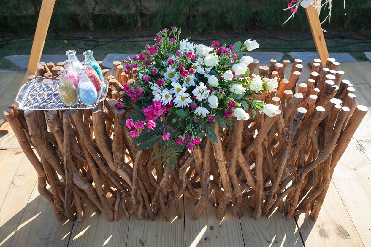 mesa com galhos de madeira e arranjo de flores brancas e cor de rosa