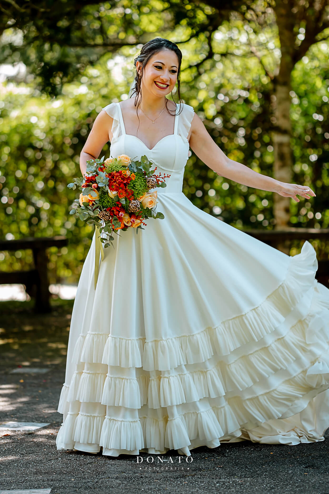 mulher segurando buquê com flores amarelas e vermelhas com vestido de noiva com babados