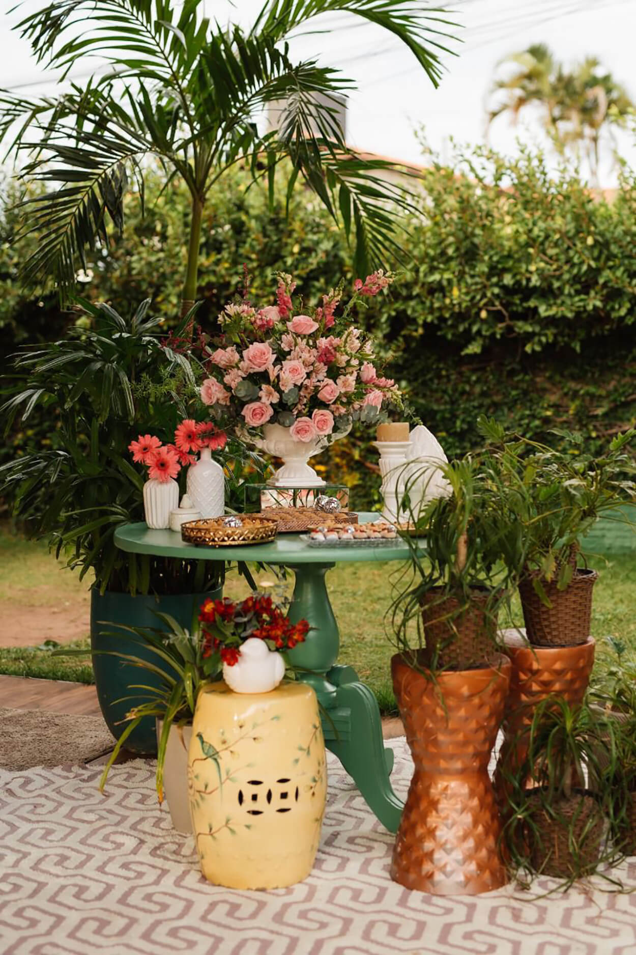 mesa verde com vasos cbranco com flores rosas