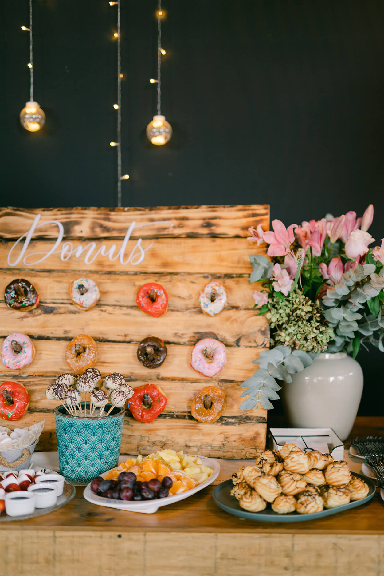 mesa de madeira com flores e painel de madeira para donuts