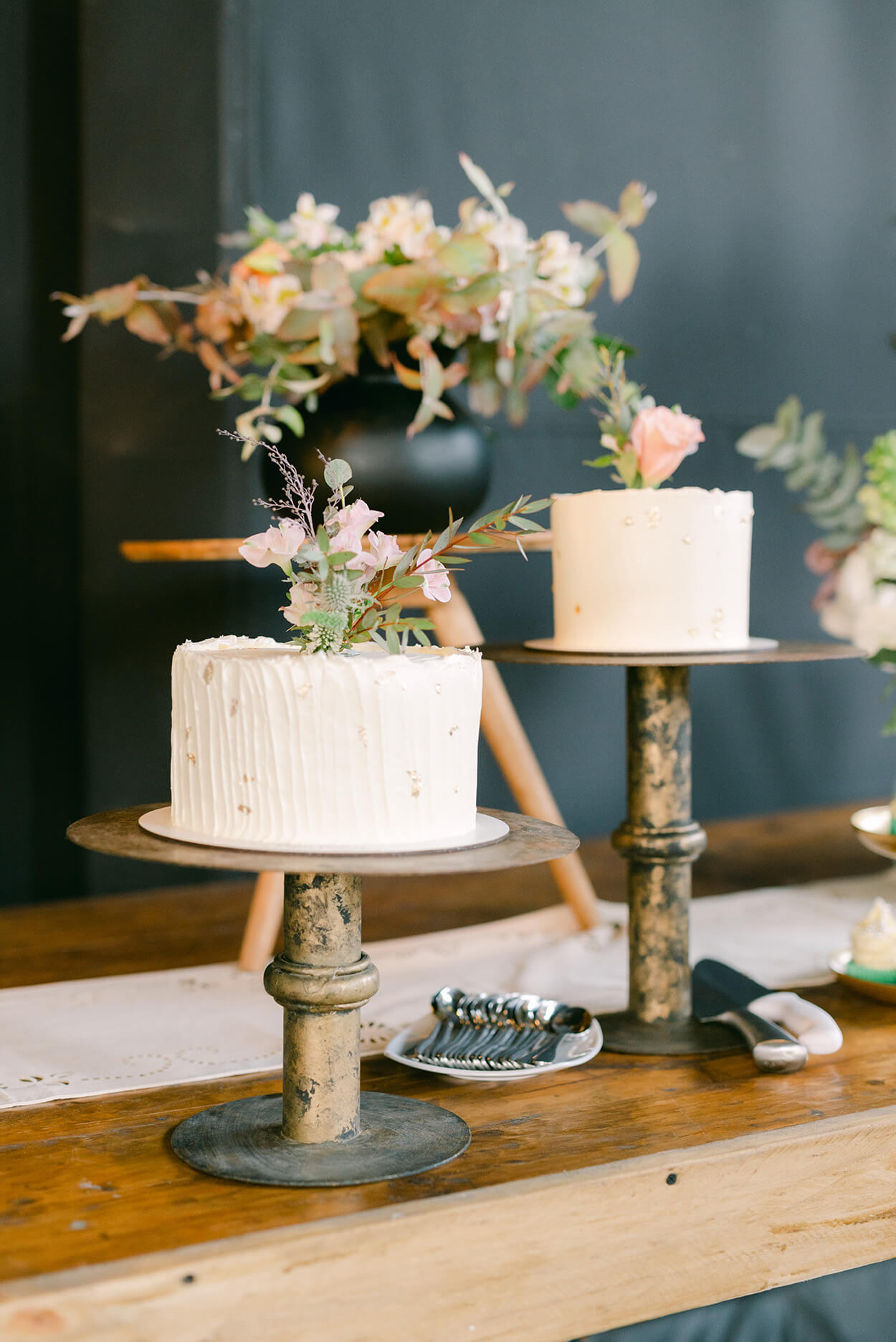 mesa com dois bolos de casamento brancos com flores no topo