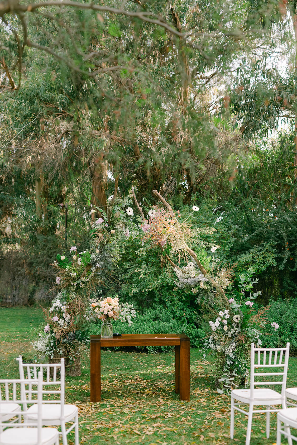 mesa d emadeira simples e rústico e arco com flores para casamento no jardim