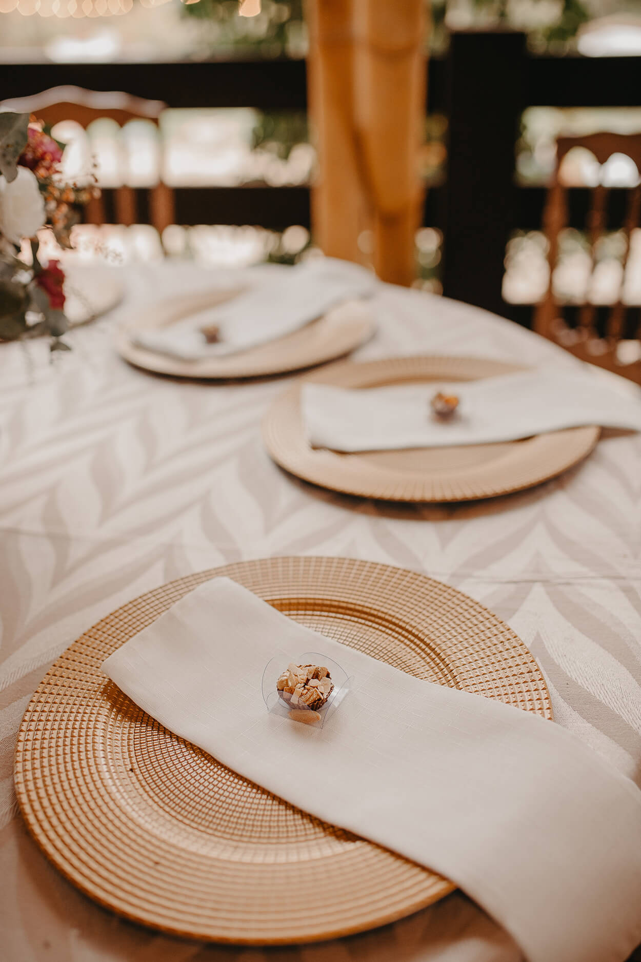 mesa posta com prato bege com guardanapo e doce em cima