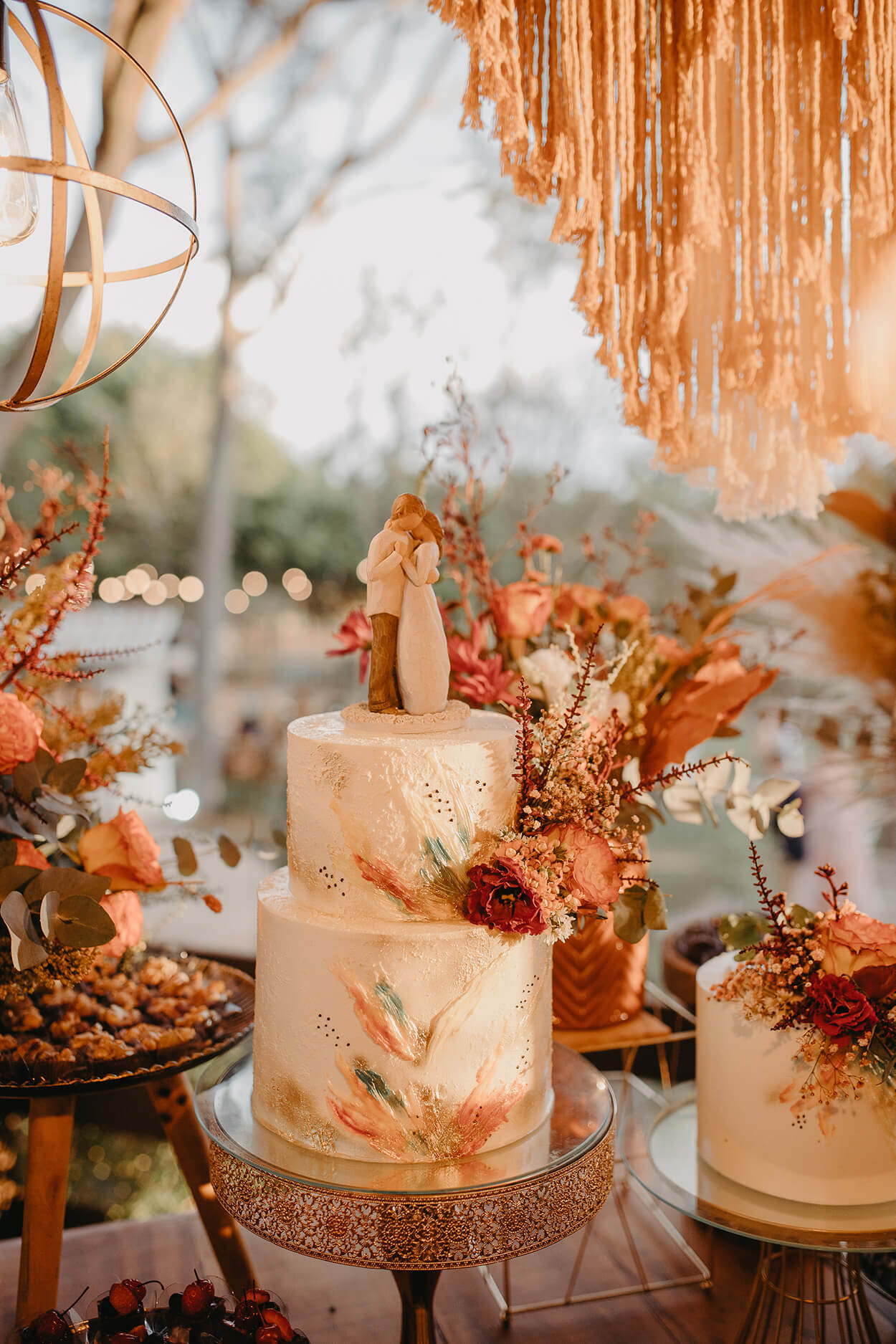bolo de casamento branco com pinceladas coloridas e bonecos no topo do bolo