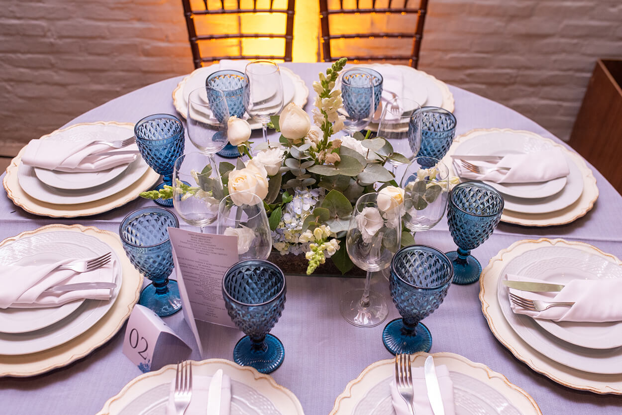 mesa posta com taças azuis e flores no centro