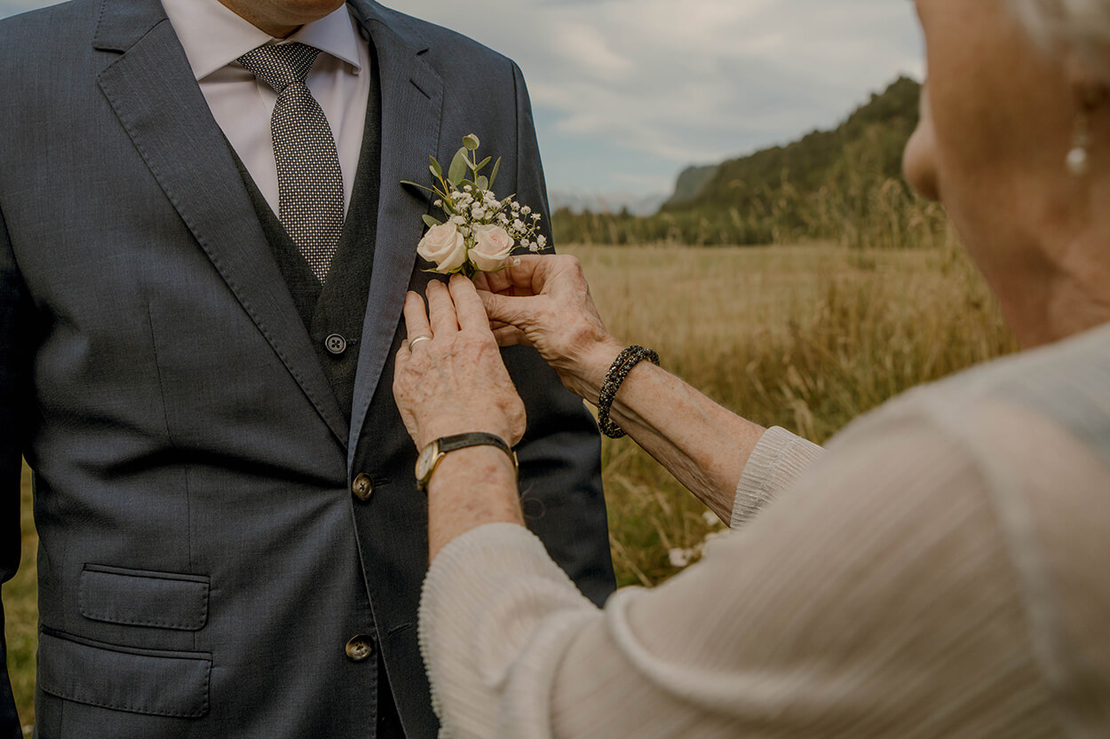 mulher colocando flor de lapela no tenro do noivo