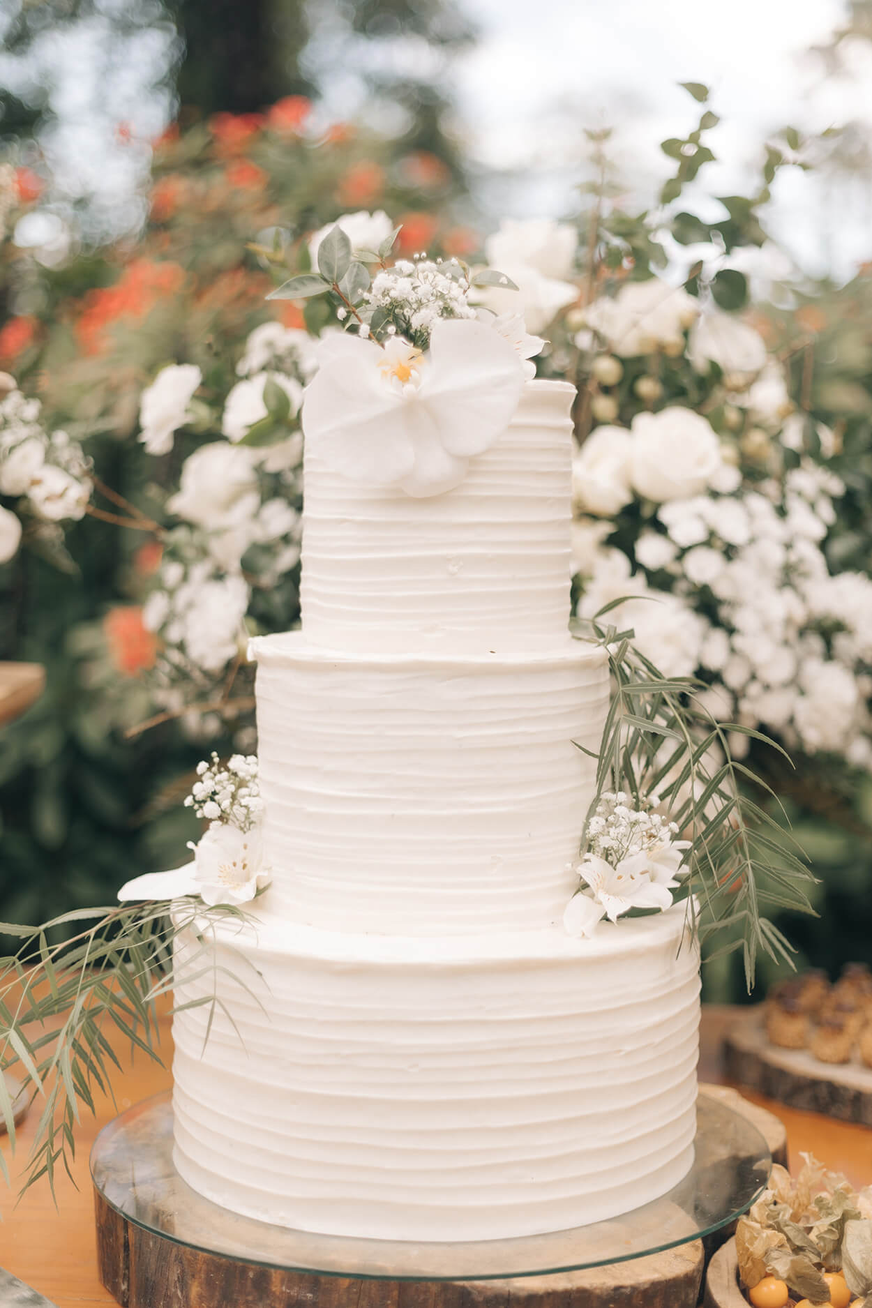 bolo de casamento espatulado com três andares e flores brancas no topo