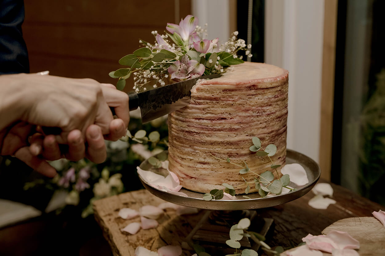 casal cortando bolo de casamento espatulado com flores no topo