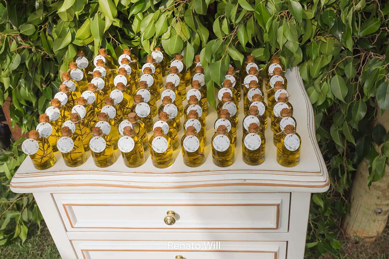 mesa branca com vidros de azeite para lembrancinha para convidados