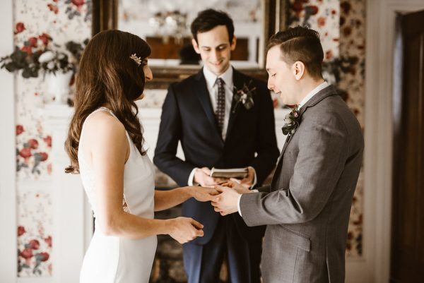 noivos na sala de estar com celebrante fazendo a leitura dos votos de casamento 