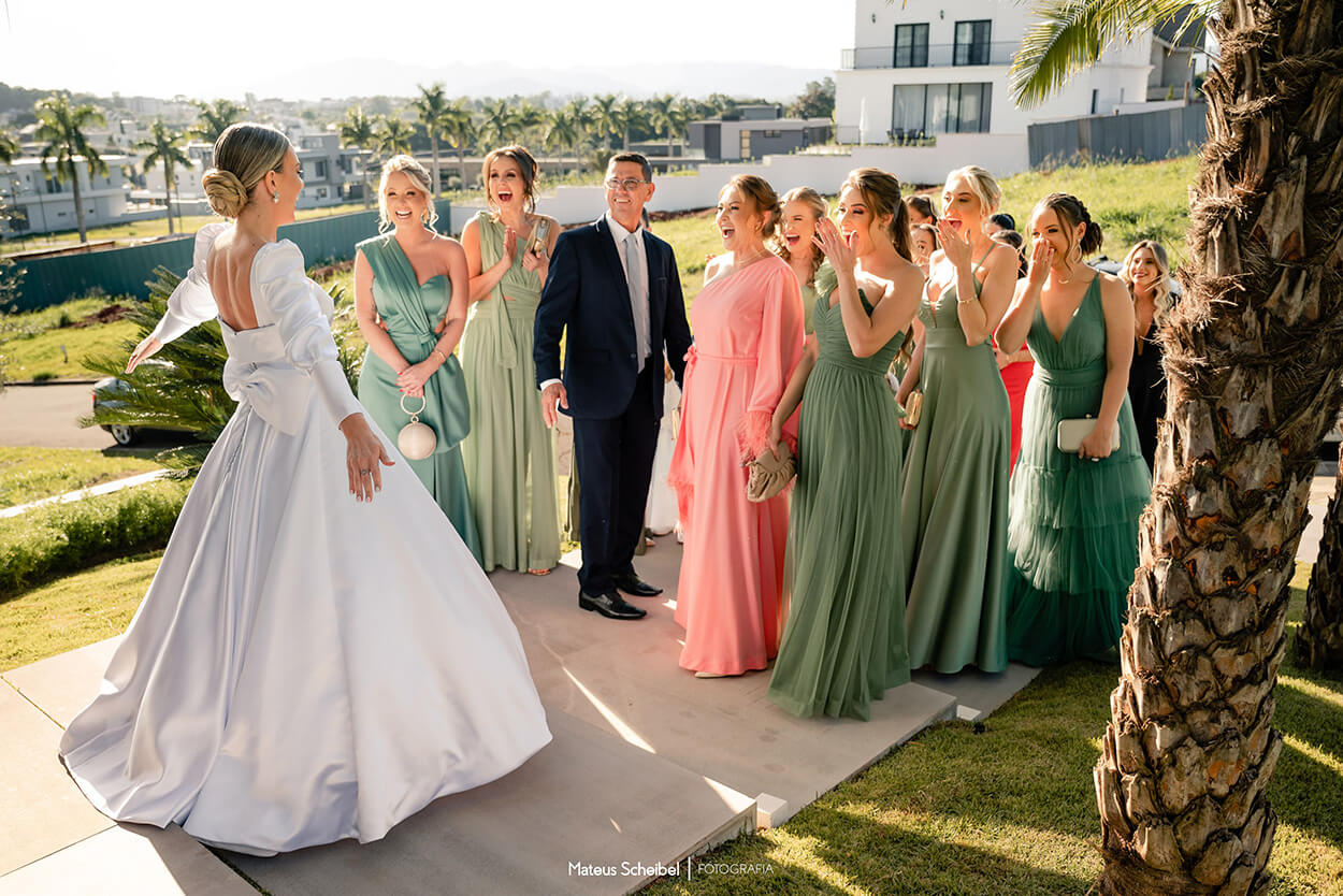 first look da noiva com as madrinhas com vestidos verdes ao ar livre